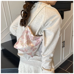 Detail of pink satin bucket bag featuring intricate gold butterfly embroidery and silver tassels