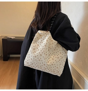 Detailed back view of a beige corduroy tote bag with heart patterns and woven straps