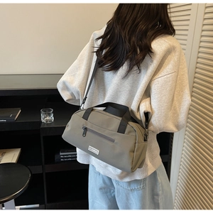 Detailed side view of a gray-green nylon crossbody bag worn by a person in a casual setting