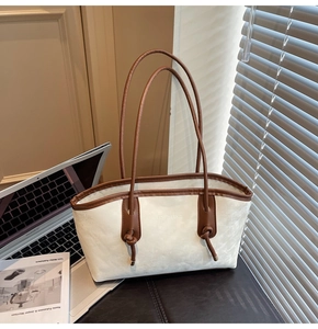 Detail view of large-capacity beige tote bag with brown leather handles and knot accents