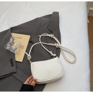 Macro detail of lychee texture and embossed logo on this cream crescent shoulder bag