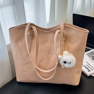 Pink tote bag with floral embossing and cute plush toy charm on a leather seat