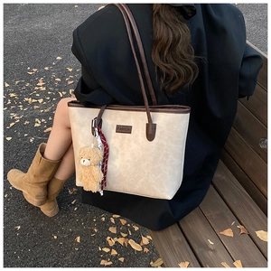 Detailed view of cream tote bag with marble texture and cute plush bear accessory