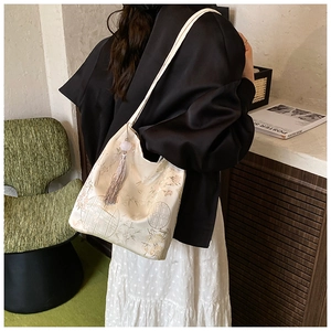 Detail showing the floral jacquard texture and silk tassel on the Neo-Chinese bucket bag