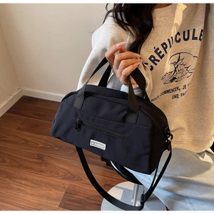 Detail of black nylon tote bag featuring front zipper pocket and JL FASHION brand label