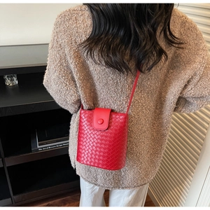 Detail of red woven bucket bag showing premium leather craftsmanship on a female model