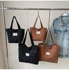 Detail view of large corduroy tote bags with heart and bow patterns in black and brown