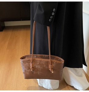 Detail of a brown vintage tote bag with knot strap design and gold hardware accents