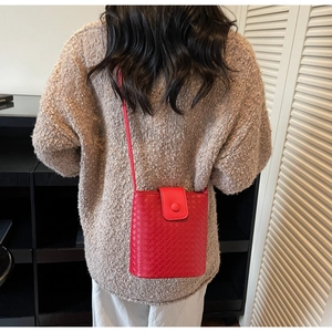 Model back view wearing a stylish red woven bucket bag with elegant crossbody strap