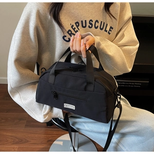 Detail of black nylon crossbody bag with JL FASHION label and zip pocket held by model