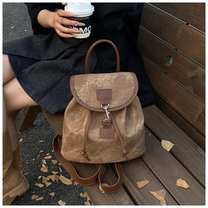 Détail d'un sac à dos vintage marron en cuir PU avec cordon de serrage sur un banc en bois