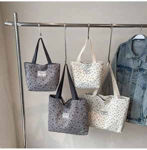 Detail of canvas tote bags with bow and heart prints in grey and cream white colors