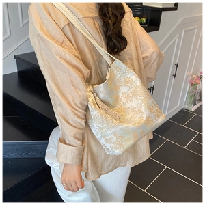 Detail of silk shoulder bag with gold landscape embroidery and silk tassel accessory