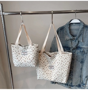 Detail of white corduroy tote bags featuring brown bow prints and woven brand labels