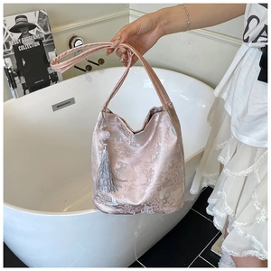Detail of pink satin shoulder bag featuring traditional Chinese embroidery and grey tassel