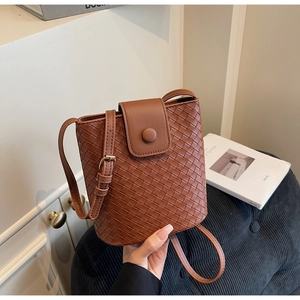 Close-up of woven caramel brown bucket bag showing detailed texture and magnetic clasp