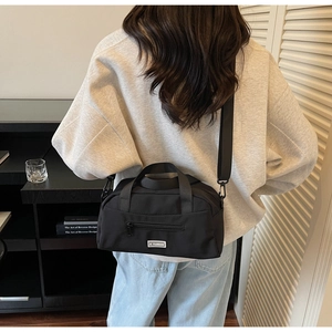 Close-up of black nylon crossbody bag with JL FASHION logo and front zipper pocket detail