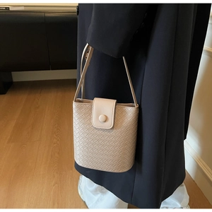 Detail of premium beige woven leather bucket bag with magnetic flap and slim shoulder strap