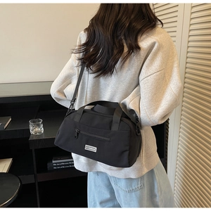 Detail of minimalist black nylon crossbody bag with JL FASHION logo and wide strap