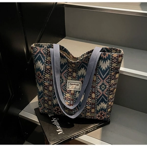 Macro view of woven ethnic tote bag featuring geometric textures and soft blue straps