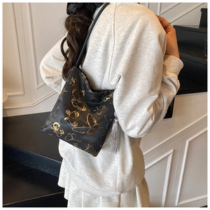 Detail of embroidered butterfly bucket bag with silver tassel and sleek black strap