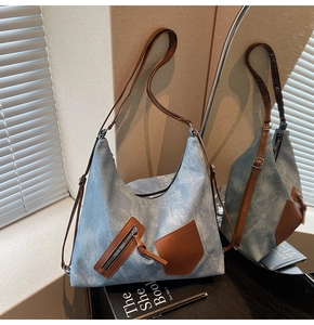 Detail of blue denim tote bag with leather straps and pocket in interior setting
