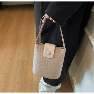 Detailed close-up of beige woven texture bucket bag with round buckle closure