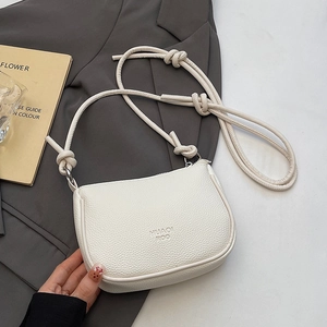 White litchi pattern leather crossbody bag with knot strap on a stylish gray blazer