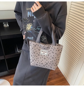 Detail of corduroy tote bag with black bow and heart print in natural lighting