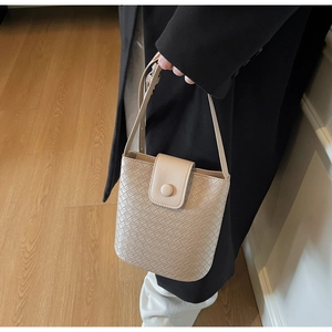 Close-up of beige woven bucket bag featuring intricate Intrecciato pattern and flap closure