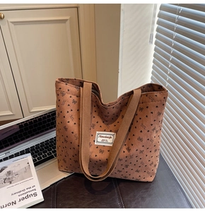 Macro detail of brown corduroy tote bag with black heart and bow pattern and woven label