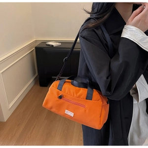 Detail of orange nylon crossbody bag with JL FASHION label and adjustable black strap