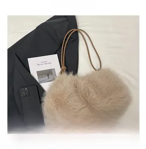 Detail of beige plush bucket bag with brown handles and gold metal ball accents