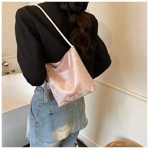 Detail of pink satin bucket bag with white landscape embroidery and grey fringe tassels