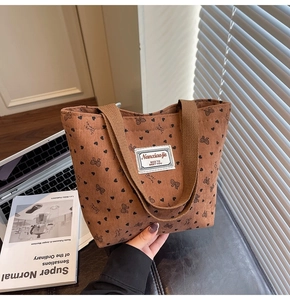 Close-up of brown corduroy tote bag featuring black heart patterns and woven handles