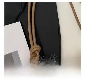 Detail of khaki leather strap with gold metal ends and soft faux fur texture on bucket bag