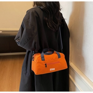 Detail of orange nylon tote bag with navy straps and JL FASHION label on model