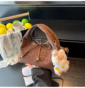 Detail of leopard print suede handbag with bow drawstring and plush bear charm
