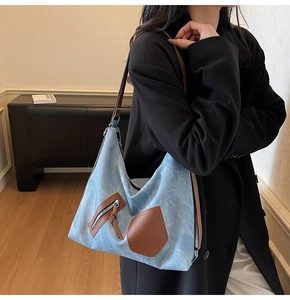 Detailed macro view of retro blue denim texture and brown leather strap on tote bag