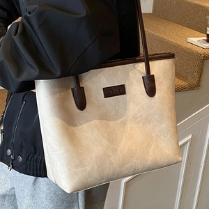 Retro cream tote bag with dark brown trim and fashion leather patch in indoor setting