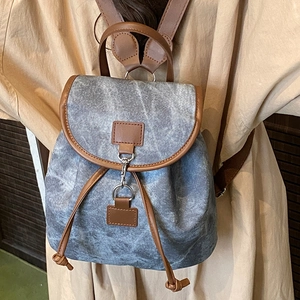 Mini sac à dos en denim bleu et cuir marron porté par un mannequin en décor décontracté