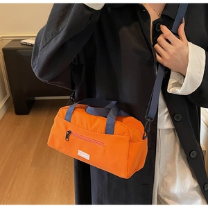 Close-up of orange nylon crossbody bag with navy straps and JL Fashion label details