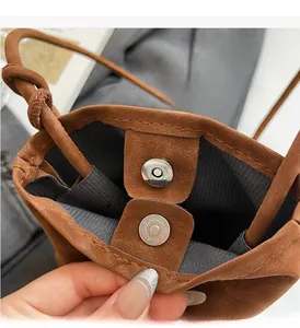 Detail of the magnetic buckle closure and striped lining on the brown suede crossbody bag