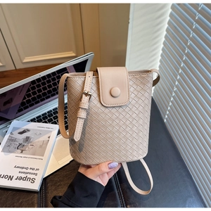 Detail of beige woven bucket bag with smooth adjustable strap and gold buckle accent