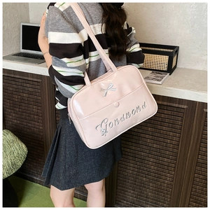 Detail of light pink faux leather tote bag with silver bow and embroidery on a model