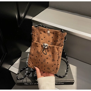 Detail of brown corduroy phone bag with bow patterns and durable woven rope shoulder strap