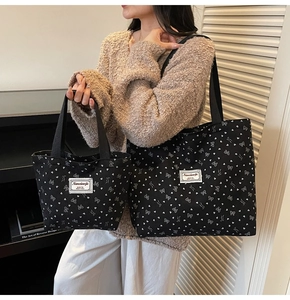 Detail of black canvas tote bag with heart patterns and white branded label tag