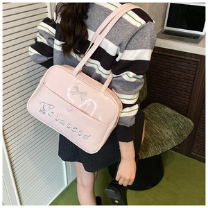 Close-up of pink patent leather tote bag with silver bow detail and logo embroidery