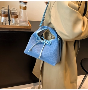 Blue leopard print pillow bag with decorative drawstring bow and adjustable strap