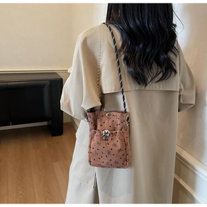 Detail of pleated corduroy crossbody bag with heart patterns on beige trench coat